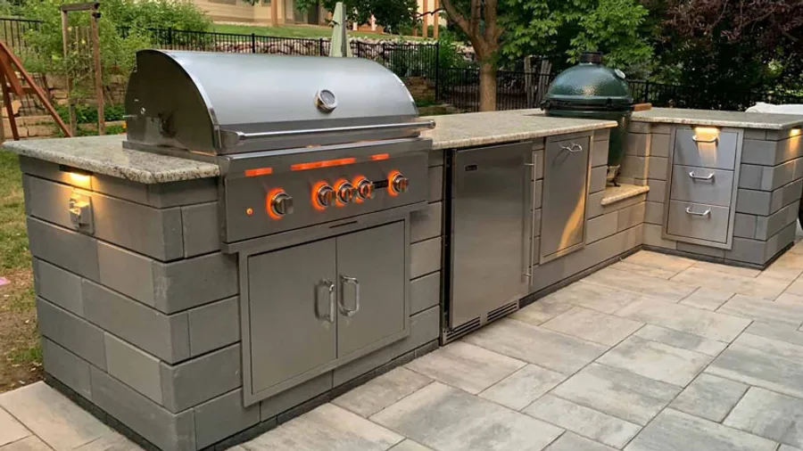 Backyard outdoor kitchen with a built-in stainless grill on a paver patio